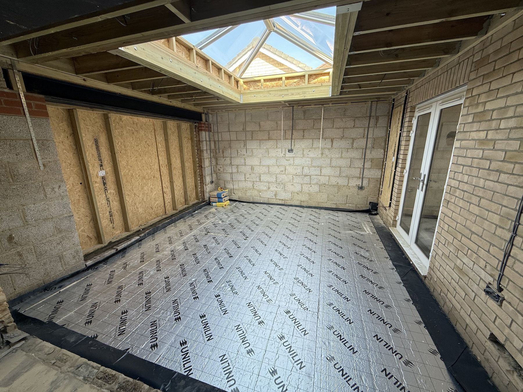 An extension at shell stage — steel goalpost in, lantern upstand framed, insulated floor laid